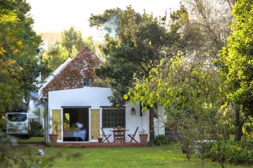a small white house with a table in the yard at Cape Weaver cottage in Greyton