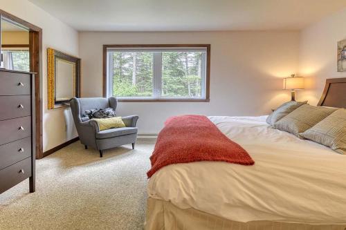 een slaapkamer met een bed, een stoel en een raam bij 146 Borealis - Close to the Mountains in Mont-Tremblant in Mont-Tremblant
