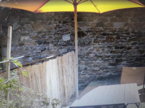 un parapluie jaune posé sur un mur de briques dans l'établissement La terrasse du champ clos, à Dinan