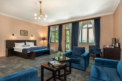 a hotel room with a bed and a couch and chairs at Hotel Bella Casa in Tbilisi City