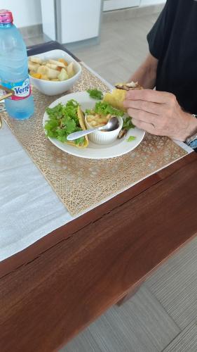 a person eating a sandwich on a table with a plate of food at Kim's Apartment in Takoradi