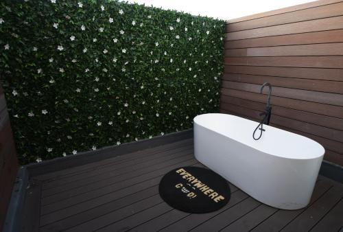 a bath tub sitting on a deck next to a hedge at Boutique Home, The Peak of Luxury in Cape Town