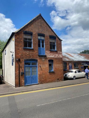 a brick building with a blue door and a car at 1 bed river apartment on the docks in Gloucester
