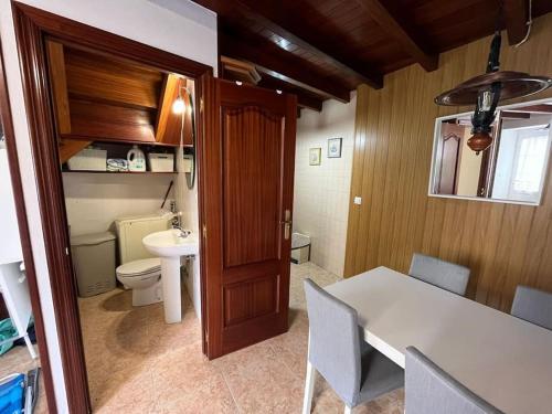 a kitchen with a table and a bathroom with a toilet at La casa del valle in Viveiro