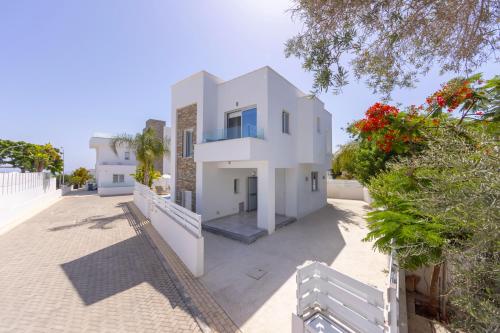 a white house with a fence and trees at Fig Tree Bay Residences 1 Lantiana Villa in Protaras