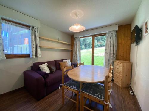 - un salon avec une table et un canapé violet dans l'établissement Iris 1 appartement T3 proche du Linga - Multipass inclu, à Châtel