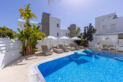 a swimming pool with lounge chairs next to a building at Fig Tree Bay Residences 1 Lantiana Villa in Protaras