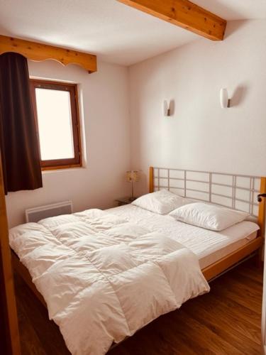 une chambre avec un grand lit blanc avec une fenêtre dans l'établissement Duplex 6 personnes les Balcons de Recoin, à Chamrousse