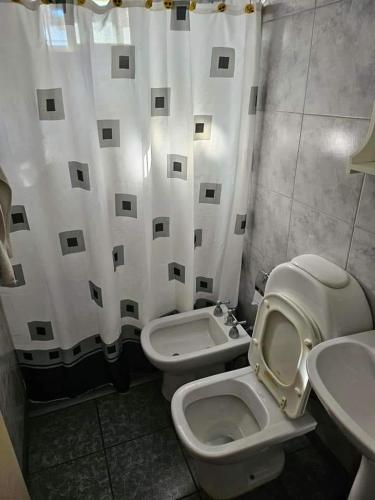 a bathroom with a toilet and a sink and a shower curtain at Refugio El Condor in Balneario El Condor