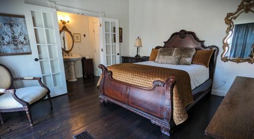 a bedroom with a large bed and a chair at The 1890 Freeman House in Galveston
