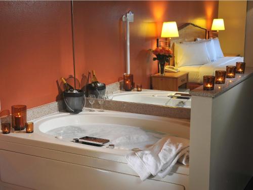 a bathroom with a tub and a bed with candles at AmericInn by Wyndham Oswego in Oswego