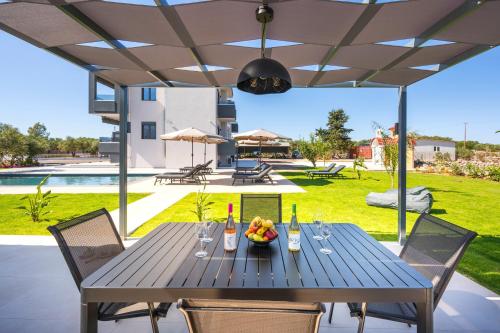 a table with wine bottles and a bowl of fruit at Luxury Oasis in Chania - Private Pool, BBQ & Garden by WeHome in Chania Town