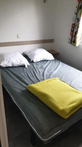 a bed with a yellow blanket on top of it at mobil home carnac in Carnac