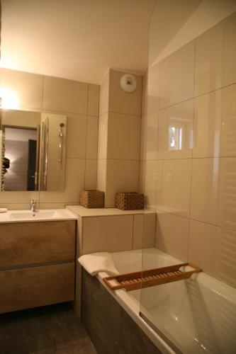 une salle de bain avec une baignoire, un lavabo et un miroir dans l'établissement Centre de bien-être Le Miel et l'Eau, à Clermont-Dessous