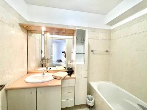 une salle de bain avec un lavabo, une baignoire et un miroir dans l'établissement Cannes Center by Welcome to Cannes, à Cannes
