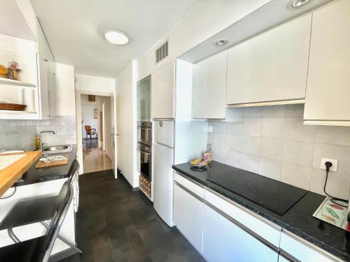 une cuisine avec des armoires blanches et des comptoirs noirs dans l'établissement Cannes Center by Welcome to Cannes, à Cannes