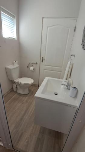 a white bathroom with a toilet and a sink at Keurbooms Getaway Studio in Plettenberg Bay