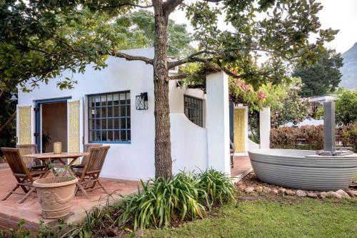 a patio with a table and a tree at Cape Weaver cottage in Greyton