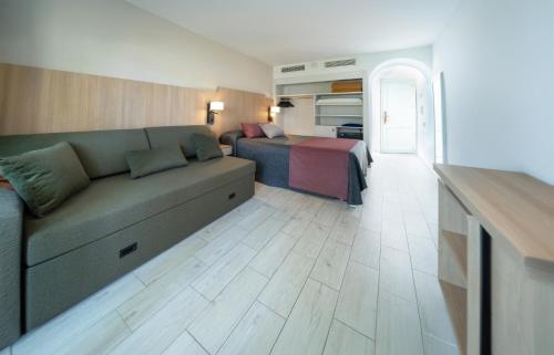 a living room with a couch and a bed at Hotel Calimera Fido Gardens in Cala d´Or