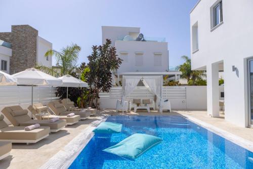 a swimming pool with chairs and an umbrella and a house at Fig Tree Bay Residences 1 Lantiana Villa in Protaras