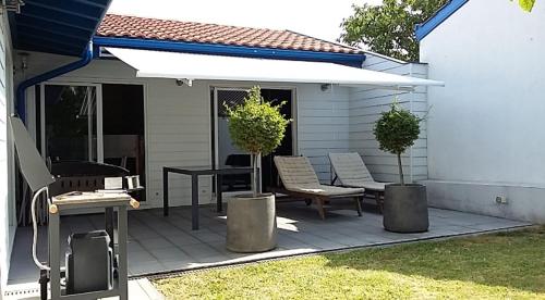 d'une terrasse avec 2 chaises, une table et un parasol blanc. dans l'établissement Villa Tarnos au calme, à Tarnos