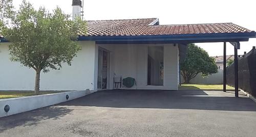 Cette petite maison blanche dispose d'une grande terrasse. dans l'établissement Villa Tarnos au calme, à Tarnos