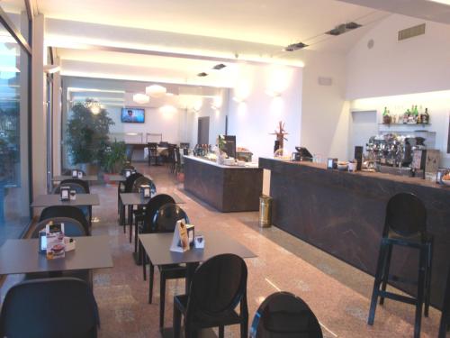 un restaurante con mesas y sillas y un bar en Hotel Pico, en Mirandola