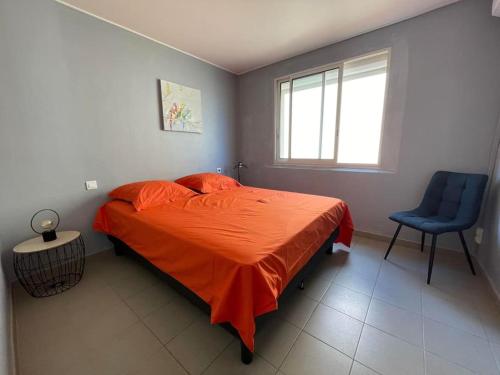 une chambre avec un lit avec une couette orange et une chaise bleue dans l'établissement Vue Panoramique front de Mer !, à Fleury