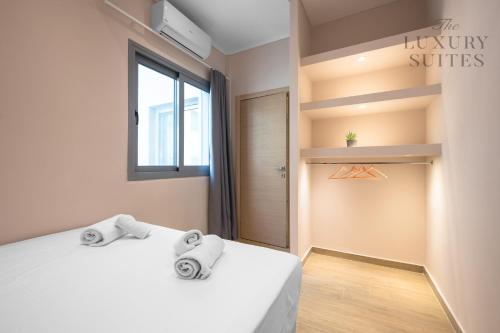 sypialnia z 2 białymi łóżkami i oknem w obiekcie Aelia Apartments, The Luxury Suites w Salonikach