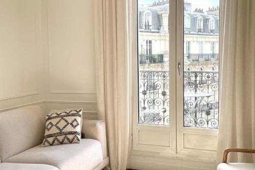 Cette chambre dispose d'une chaise et d'une porte en verre avec une fenêtre. dans l'établissement Elegant Haussmann Parisian flat close Eiffel Tower, à Paris