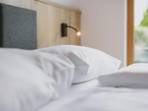 a bed with white pillows and a lamp on it at First IN Mountain Chalets by we rent in Kaprun