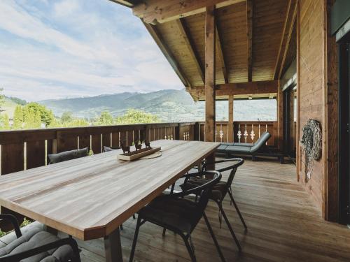 a large wooden table on a deck with chairs at First IN Mountain Chalets by we rent in Kaprun