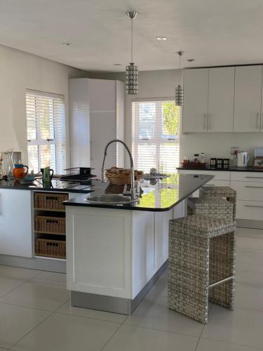 a kitchen with white cabinets and a kitchen island with a sink at Bed and Breakfast Villa Livadia in Cape Town