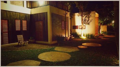 a house with a bench in the yard at night at แอทชฎา เชียงใหม่ @Shada Chiang Mai in Chom Thong