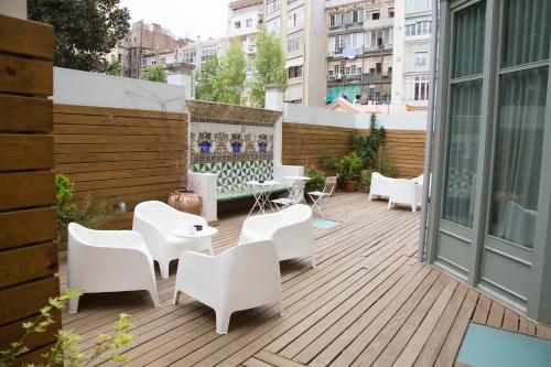 um pátio no último piso com cadeiras e mesas brancas em Casa Mathilda em Barcelona