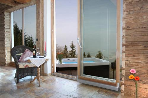 a patio with a tub and a table and a chair at Schönblick Hohenbogen in Neukirchen beim Heiligen Blut
