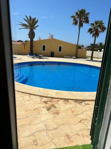 a swimming pool with palm trees and a building at Apartamento Siete Pameras 1 in Cala en Blanes
