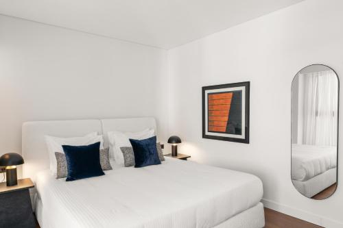 a white bedroom with a white bed with blue pillows at The Athenaeum Luxury Hotel in Athens
