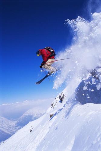 a man flying through the air while riding skis in the snow at Chalet Jean in Grimentz