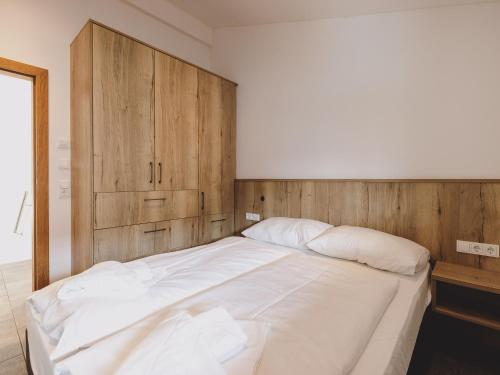 a bedroom with a large white bed with a wooden headboard at First IN Mountain Chalets by we rent in Kaprun