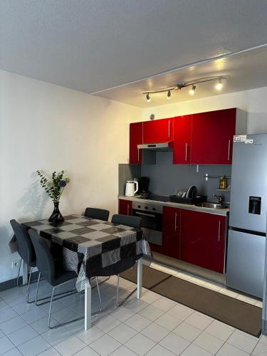 La cuisine est équipée de placards rouges, d'une table et d'un réfrigérateur. dans l'établissement Californie, à Nice
