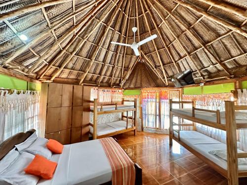 Habitación con 2 camas y techo de paja. en Eco Hostal Yuluka en El Zaino