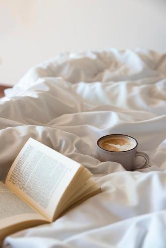an open book and a cup of coffee on a bed at Der Waldhof in Vollan