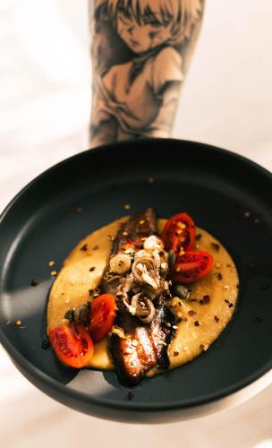 a black plate with a pizza with tomatoes and mushrooms at Acron Suites in Limenaria