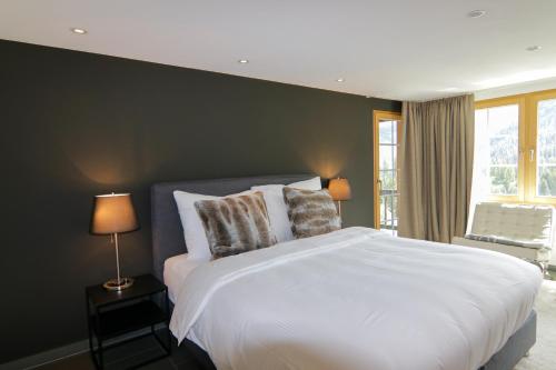 a bedroom with a white bed and a window at Chalet Badrutt by Arosa Holiday in Arosa