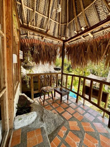 an outdoor room with a table and a straw roof at Eco Hostal Yuluka in El Zaino