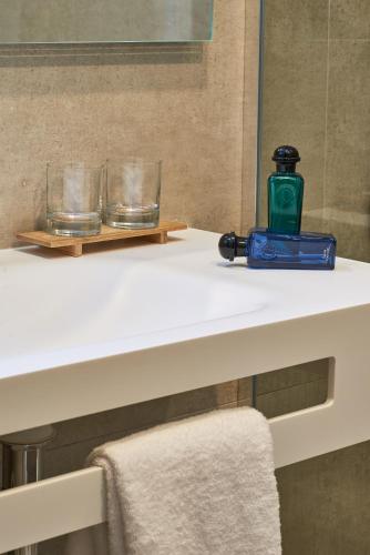 a bathroom counter with a bottle and glasses on it at Mercure Paris Nanterre in Nanterre