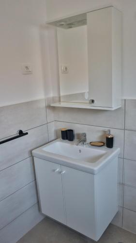 a white bathroom with a sink and white cabinets at Zelena oaza in Krk