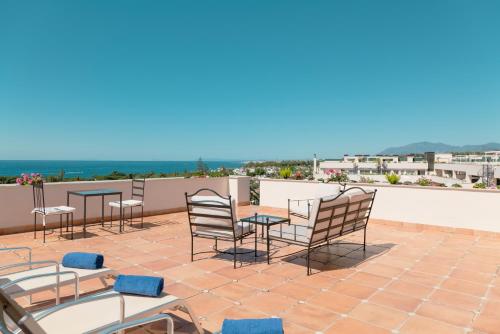 a patio with tables and chairs on a roof at Guadalpin Suites in Marbella