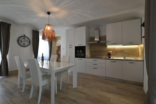 eine Küche mit einem weißen Tisch und weißen Stühlen in der Unterkunft La perla di Asti con Jacuzzi e Sauna in Asti